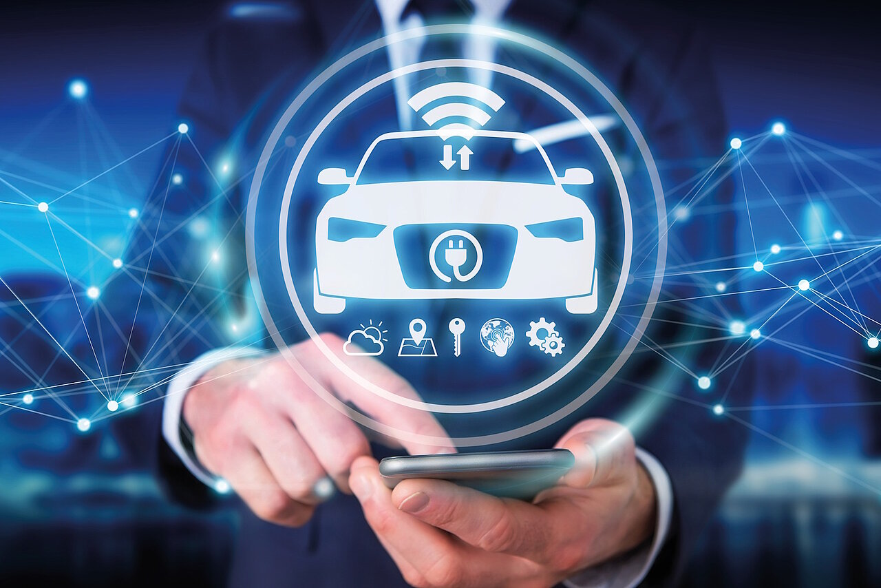 Ein Mann tippt auf sein Smartphone, es erscheint ein Hologramm mit Pkw und Icons rund um Digitalisierung.