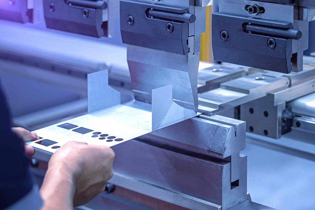 Ein Arbeiter legt eine Blech in eine Maschine, das so gebogen wird.